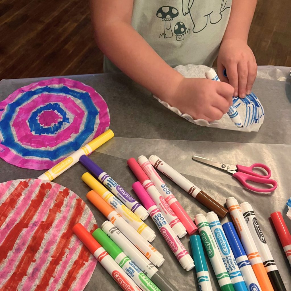 kid coloring on a coffee filter with washable markers