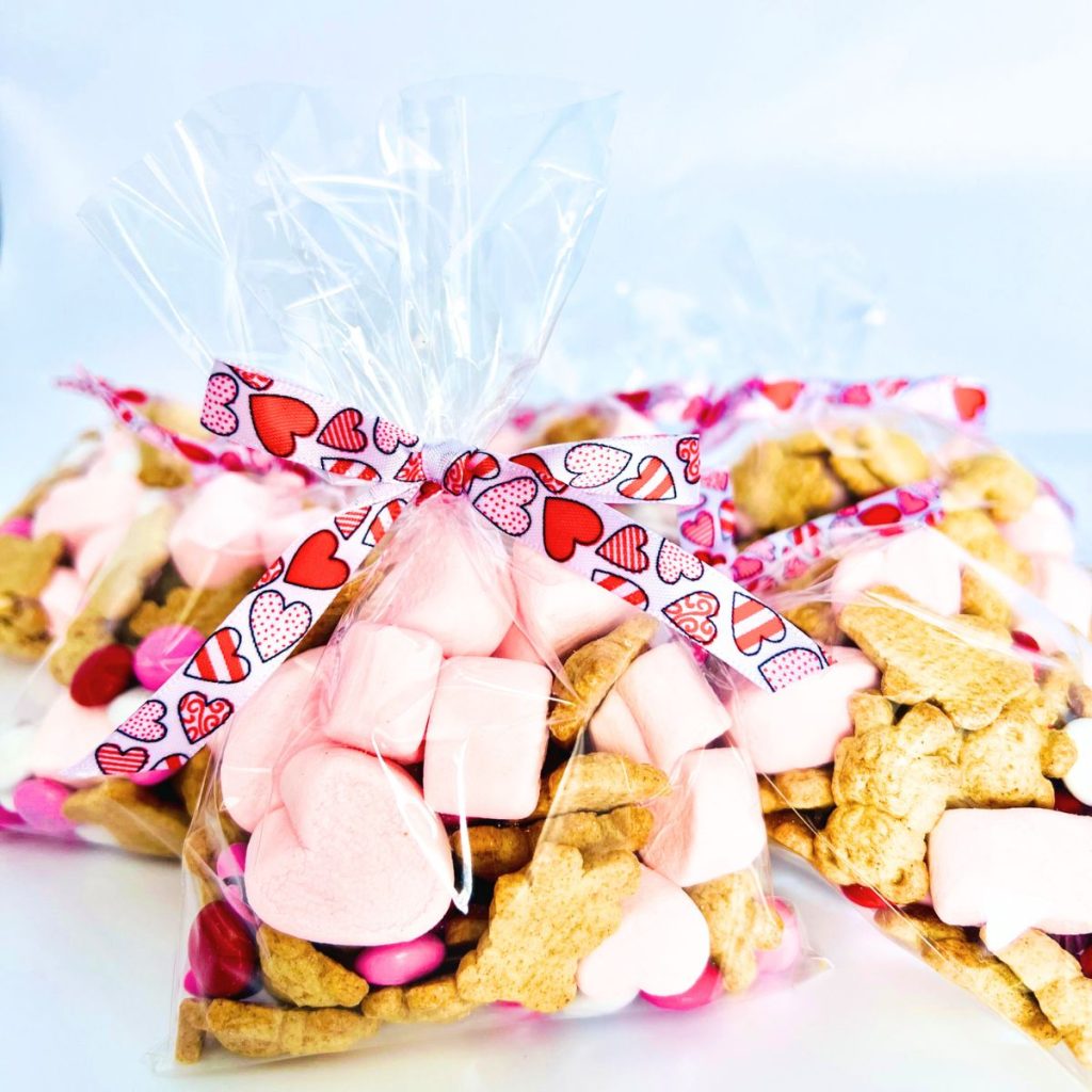 Valentine snack mix strawberry heart shaped marshmallows m&ms and cinnamon teddy grahams in a cello bag with a ribbon