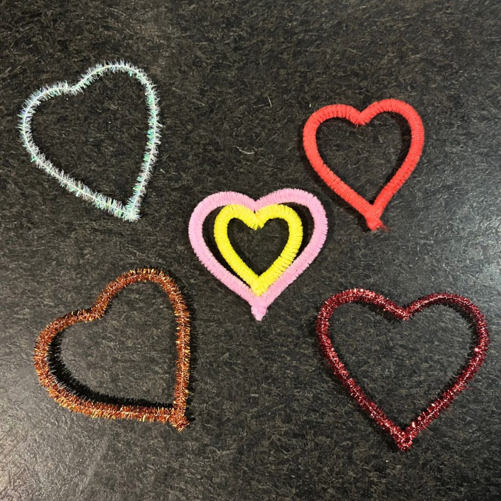 pipe cleaner hearts red pink brown silver yellow on black countertop