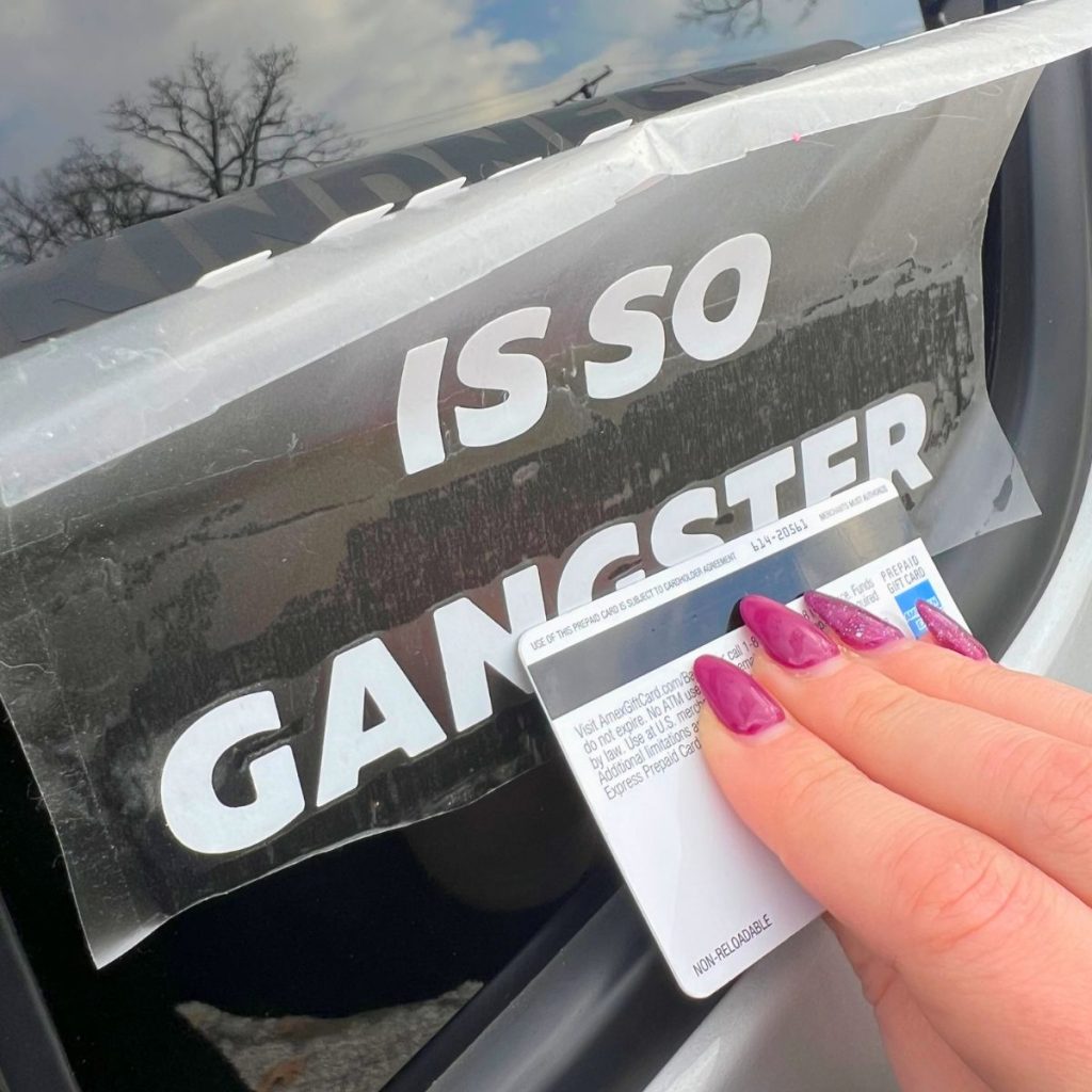 car decal being placed on car window with credit card