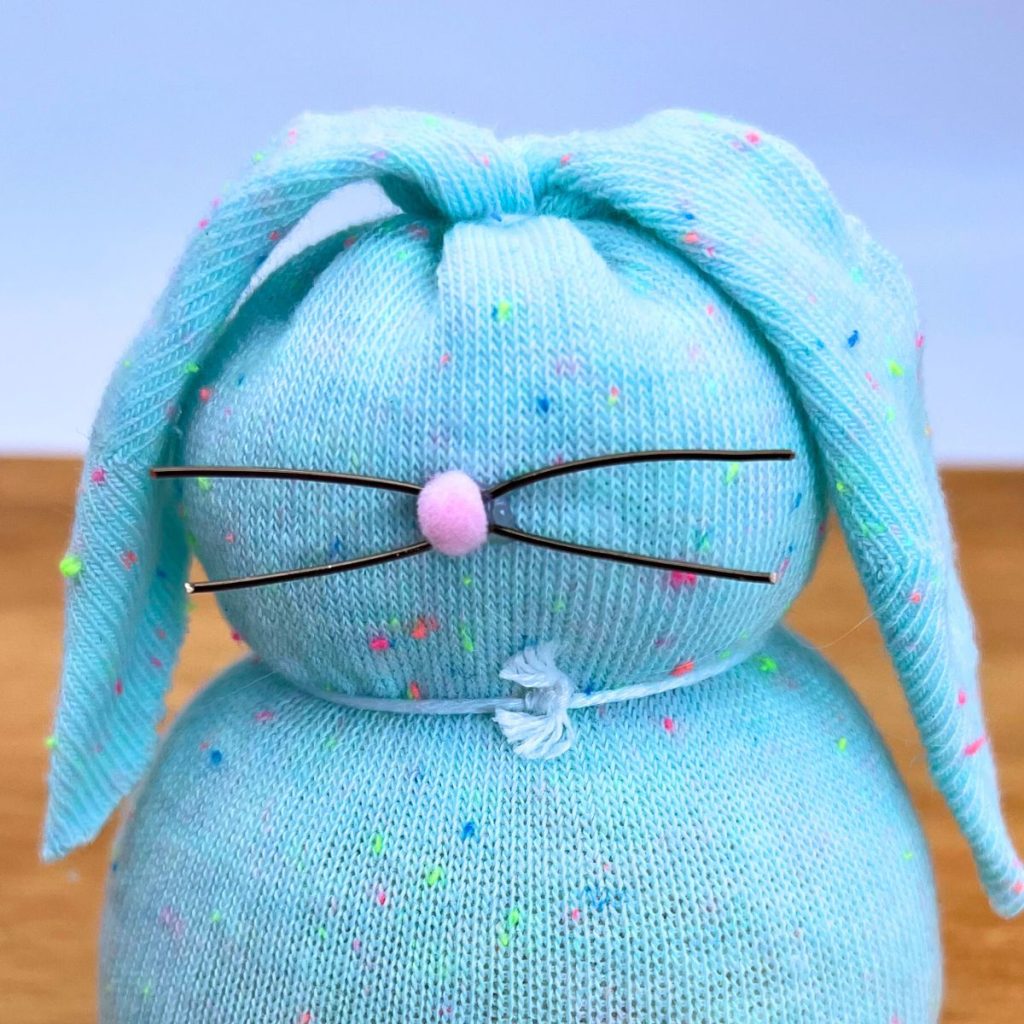 blue sock bunny filled with rice, wire whiskers and pink pom pom nose. 