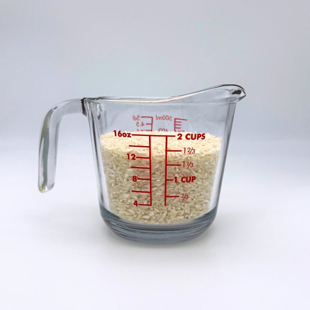 long grain white rice in measuring cup on counter