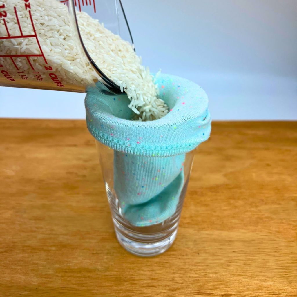 blue sock in a glass with long grain rice pouring into the sock.