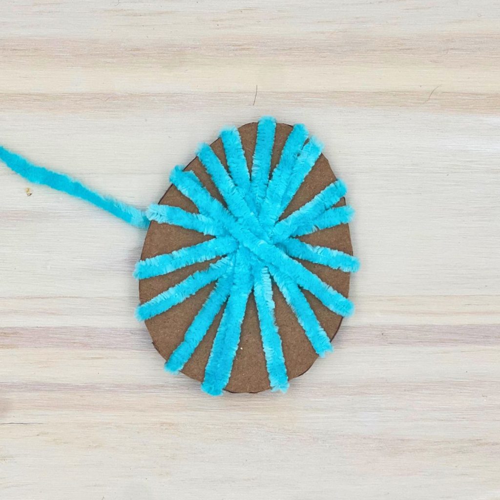 cardboard easter egg wrapped in blue yarn to make garland